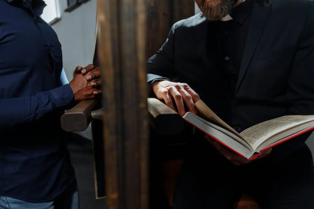 A priest listening to a man's confession inside a church, symbolizing faith and spirituality.